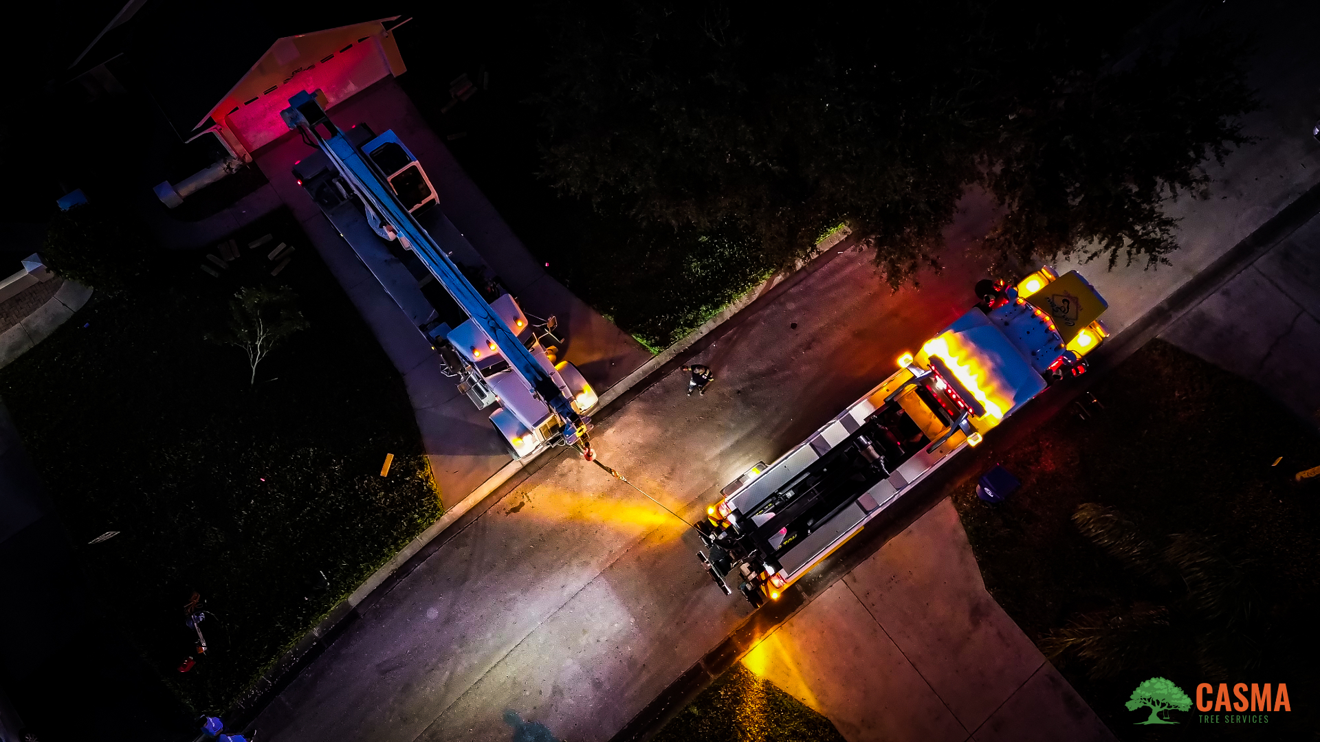 Aerial night view of Casma crane and dump truck staged on a residential street